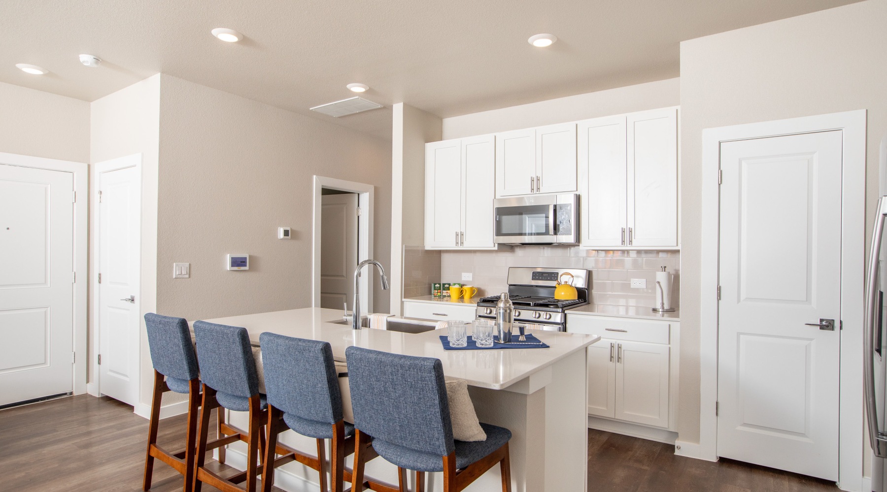 kitchen with blue barstool high chairs, eat-in island, and white cabinets