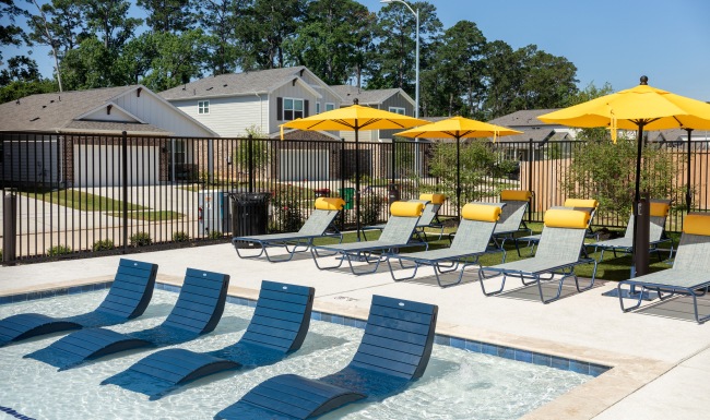 pool image with lounge chairs in front and chairs with umbrellas in the back
