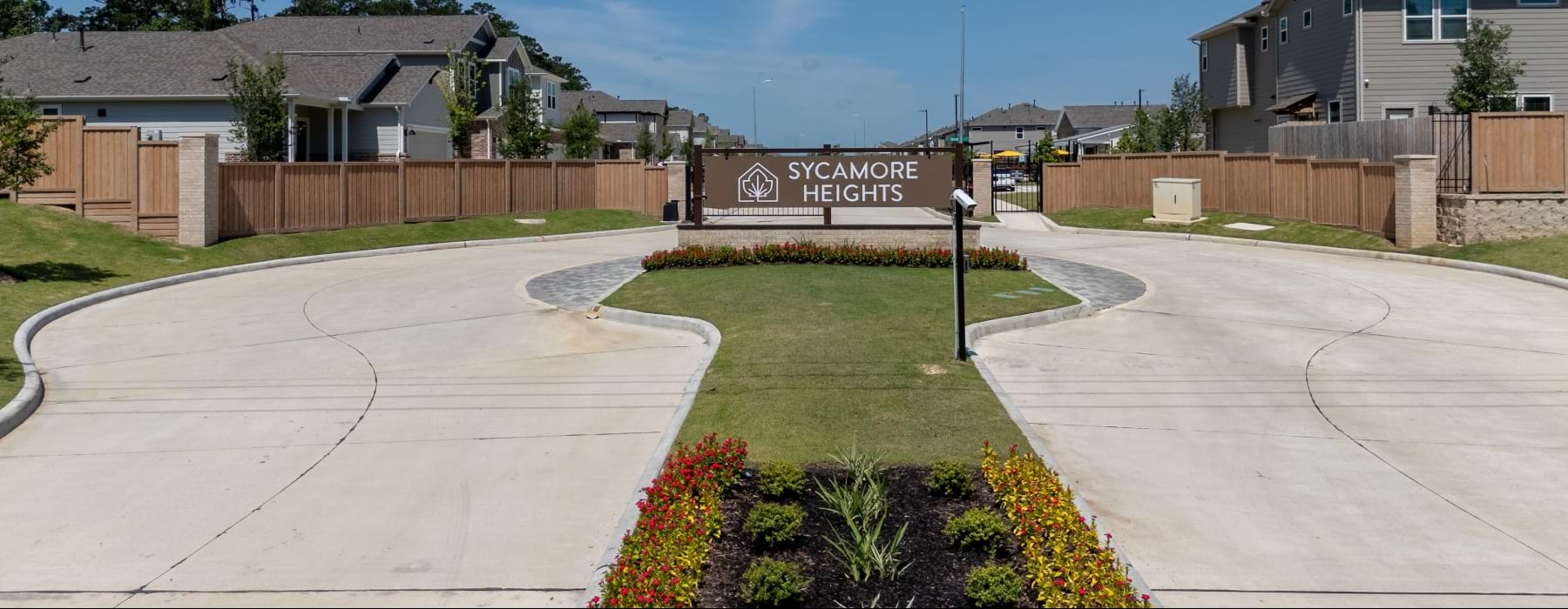 monument sign that says Sycamore Heighs with colorful flowers in front